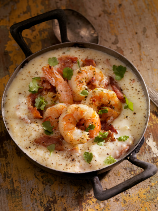 Shrimp and bacon on a grits in a cast iron pot, sprinkled with parsley. 